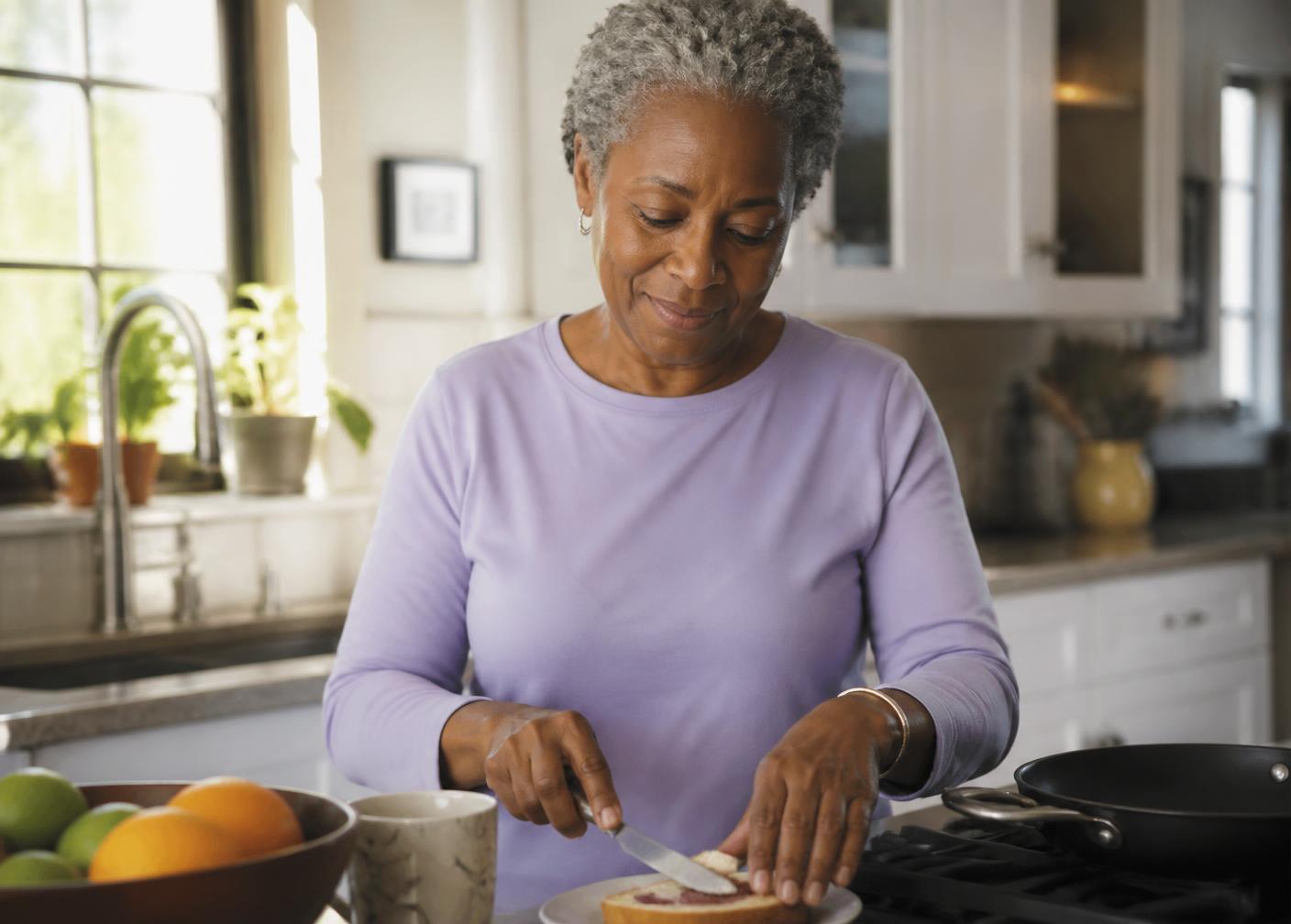 A woman preparing breakfast in her sunlit kitchen.